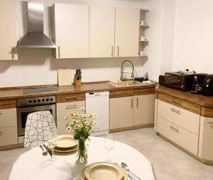 a kitchen with white cabinets and a white table with flowers at Schönes Apartment mit Pool&Sauna in Bingen am Rhein