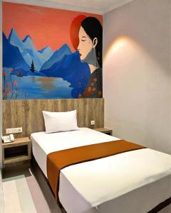 a bedroom with a painting of a woman at Bless Red Hotels in Sintang