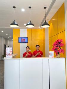 two men standing behind a counter in an office at Bless Red Hotels in Sintang
