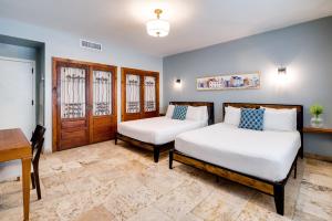 two beds in a room with a table and a desk at Kasa Impala Miami Beach in Miami Beach