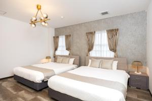 a bedroom with two beds and a chandelier at Bijou Suites AI PREMIUM in Osaka