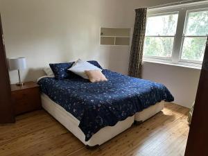 a bedroom with a bed with blue sheets and a window at Gracious 1930s Art Deco House in Gosford