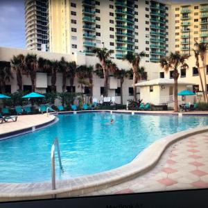 a large swimming pool with palm trees and a large building at Oceanfront retreat, Hollywood Beach ,Miami Florida in Hollywood +46 photos