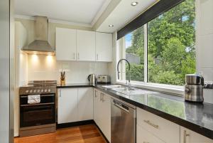 a kitchen with white cabinets and a large window at Belle in Bowral in Bowral