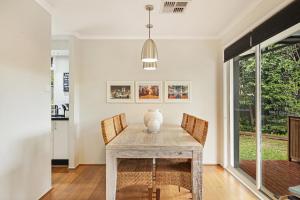a dining room with a table with chairs and a vase on it at Belle in Bowral in Bowral