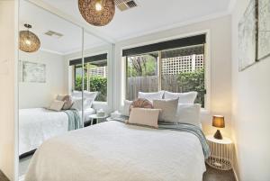 two beds in a room with two windows at Belle in Bowral in Bowral
