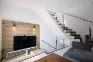 a living room with a large television and a staircase at Attic Center Sitges in Sitges