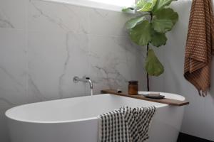 a white bath tub in a bathroom with a plant at Sea Notes Yamba in Yamba