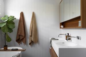 a white bathroom with a sink and a mirror at Sea Notes Yamba in Yamba