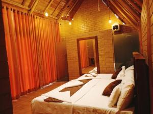 a large bed in a room with orange curtains at Deduru Oya Cinnamon Gardens in Barandara