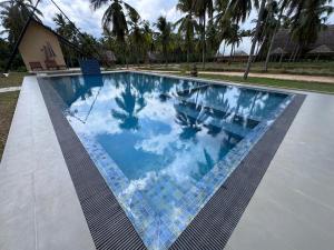 a swimming pool with a reflection of the sky in the water at Deduru Oya Cinnamon Gardens in Barandara
