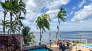 a group of people sitting around a swimming pool next to the ocean at Tropical Executive 924 in Manaus