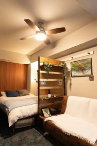 a bedroom with two beds and a ceiling fan at Tanuki Inn Korien Kyoto Osaka in Neyagawa