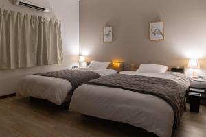 a hotel room with two beds and a window at 勝山駅徒歩1分 恐竜博物館車5分スキージャム15分 BBQ可能 シアタールーム Kidsルーム完備 駅前好立地 in Katsuyama