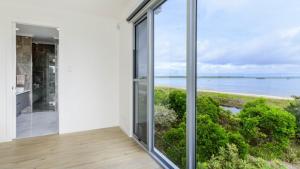 a room with a large window with a view of the water at Solander Sanctuary By The Water in Banksia Beach