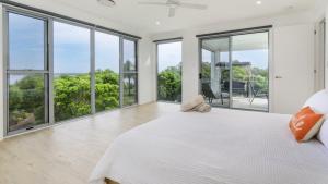 a white bedroom with large windows and a large bed at Solander Sanctuary By The Water in Banksia Beach
