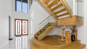 a staircase in a home with white walls and wooden floors at Solander Sanctuary By The Water in Banksia Beach