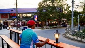 a man sitting on a bench with a light at Tiny house bangtao phuket in Ban Thalat Choeng Thale