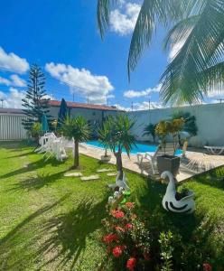 a yard with a swimming pool with swans and palm trees at Casa temporada frances in Marechal Deodoro