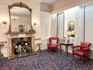 a living room with a fireplace and two red chairs at Dergvale Hotel in Dublin