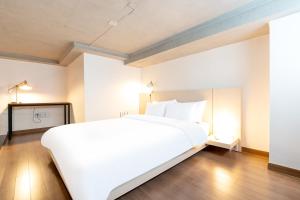 a large white bed in a room with a wooden floor at 진우 프레스티지 호텔 in Okp'o-ri
