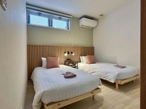 two beds in a room with a window at Akayane Lodge by H2 Life in Nakafurano