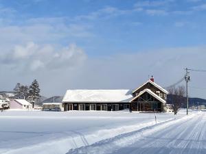 a building covered in snow with a snow covered road at Akayane Lodge by H2 Life in Nakafurano