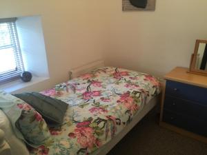 a bedroom with a bed with a floral bedspread at Cottage on the Green in Brackley