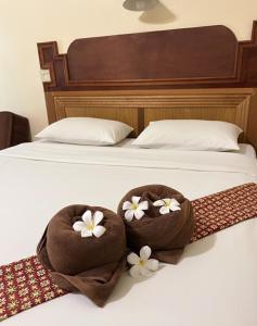 two towels with flowers are sitting on a bed at Phu Lanta Life Resort in Ko Lanta