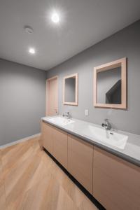a bathroom with two sinks and two mirrors at The KAMUY FURANO in Nakafurano