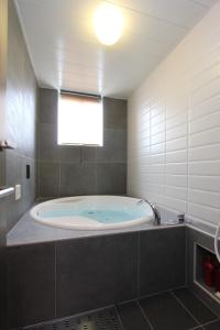 a large bath tub in a bathroom with a window at HOTEL DCUBE in Tokyo