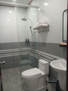 a bathroom with a shower and a toilet and a sink at Nhi Quỳnh La Gi Hotel in Lagi