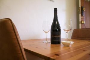 a bottle of wine sitting on a table with two glasses at Kaesler Cottages in Nuriootpa