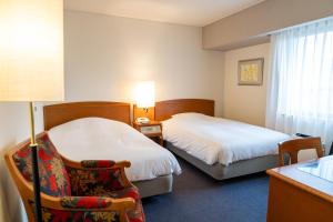 a hotel room with two beds and a chair at Mori-no-Hotel Sendai in Sendai
