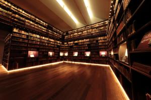 a large library with a wooden floor and lots of books at HOTEL DCUBE in Tokyo
