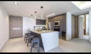 a kitchen with a counter and stools in a room at Sonoran Star Signature 3-Bedroom Beachfront Luxury Condominium in Puerto Peñasco