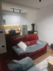a red couch in a living room with a kitchen at Vila Davidoski in Mavrovo