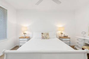 a white bedroom with a large white bed and two night stands at Coastal House in Gold Coast