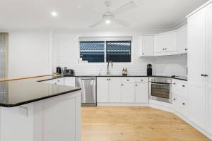 a white kitchen with white cabinets and a wooden floor at Coastal House in Gold Coast