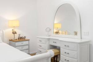 a white bedroom with a white dresser and a mirror at Coastal House in Gold Coast