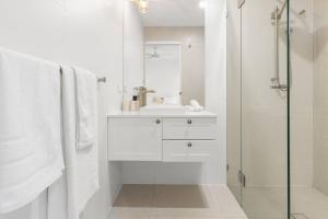 a white bathroom with a sink and a shower at Coastal House in Gold Coast