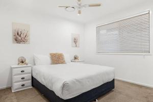 a white bedroom with a bed and a window at Coastal House in Gold Coast +20 photos