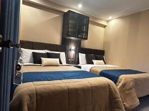 a bedroom with two beds and a tv on the wall at Gran Hotel in Yungay