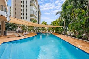 a large swimming pool with a large umbrella over it at Corner Balcony Suite on the Esplanade with Pool in Darwin