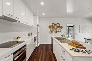a kitchen with white cabinets and a wooden floor at Hartzell One Seven - Private - Family Friendly in Wilyabrup
