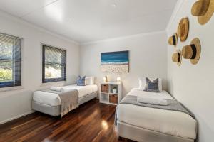 two beds in a room with white walls and wood floors at Hartzell One Seven - Private - Family Friendly in Wilyabrup