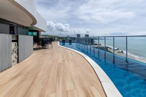 a balcony with a swimming pool and the ocean at RN Studio Premium – Your Seaside Retreat in Maceió