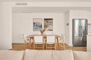 a dining room with a table and chairs and a refrigerator at Salt Tugun in Gold Coast