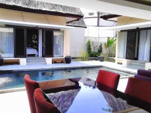a swimming pool with red chairs next to a house at Kampung Sumber Alam Garut in Garut