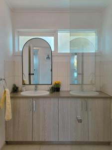 a bathroom with two sinks and a mirror at Sitara Cottage in Yanakie